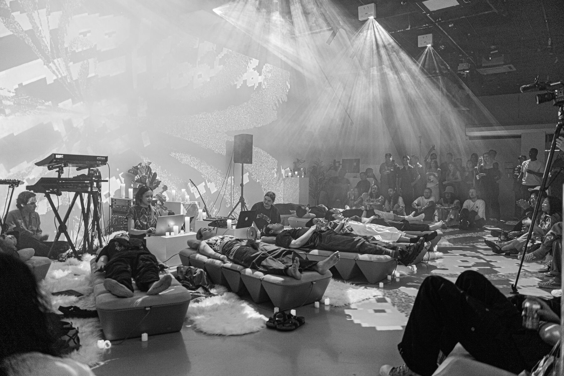 A full room: the octagon lit by projector beams, a crowd seated along the walls.